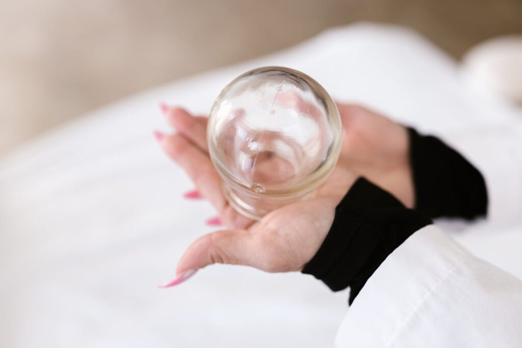 Close-up view of hands holding a glass used for cupping therapy in physiotherapy settings.